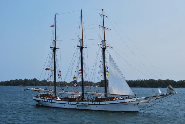 a tall white boat with people sailing down a river