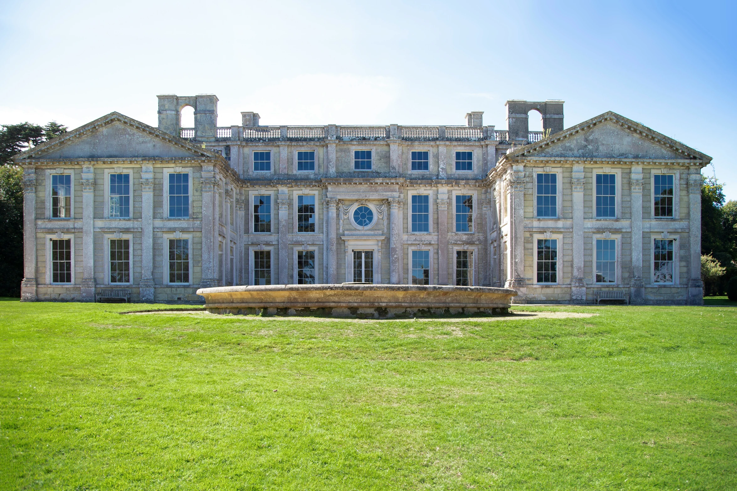 the house in the field has large, stone and white trim