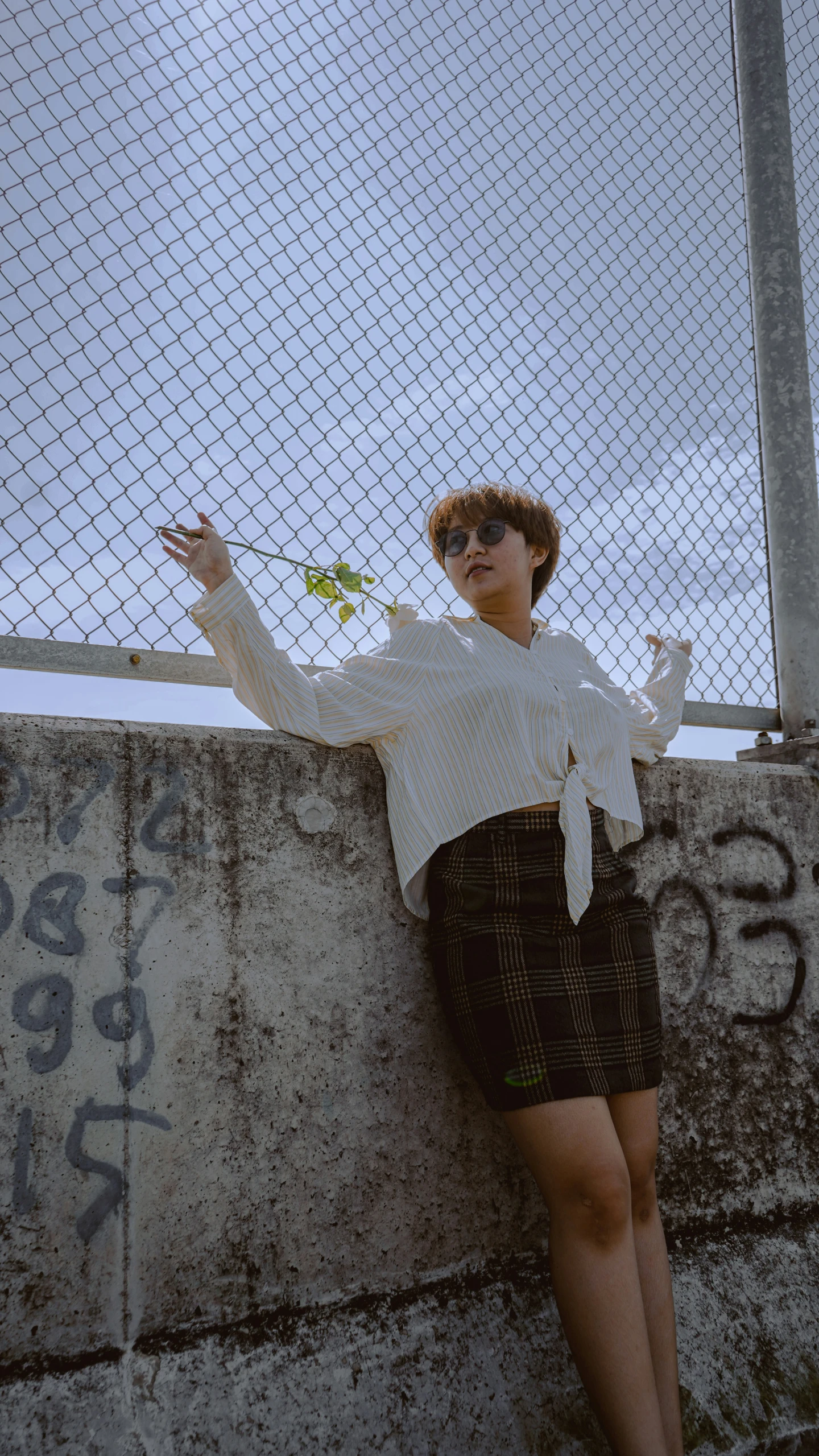 a young lady leaning against the side of a fence