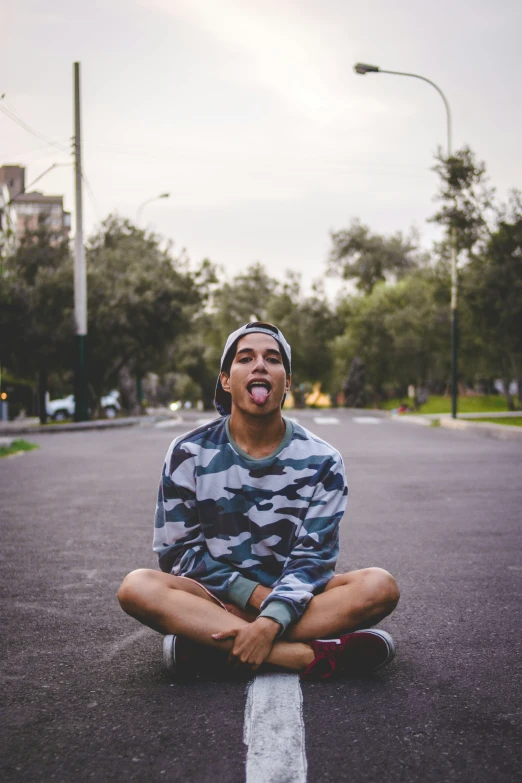 man sits on street and smiles with crossed arms