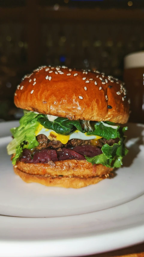 a large burger sits on a plate with a cup of beverage