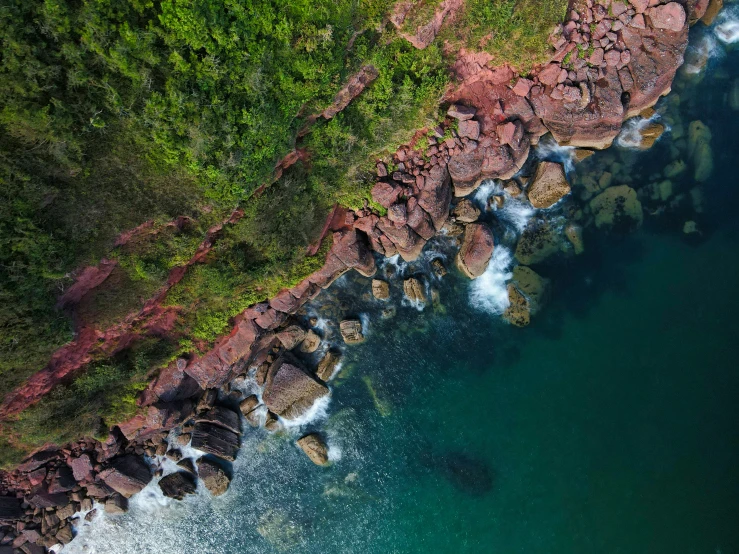 an aerial view of a green cliff with blue water