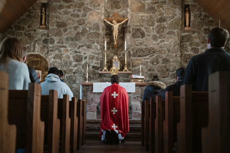 a person in a red robe sitting on the pews of a church