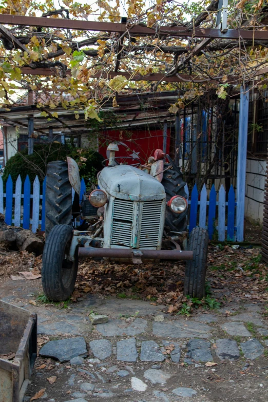 a large truck with lots of tires is parked near a blue fence