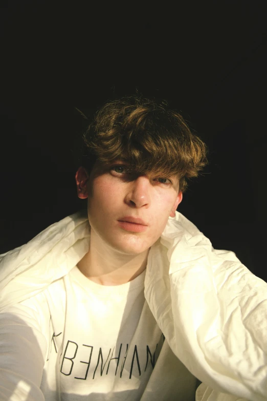 a boy wearing a white sweater holding a white shirt on his head