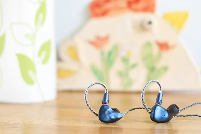 the in - ear headphones are blue and have silver metal strings