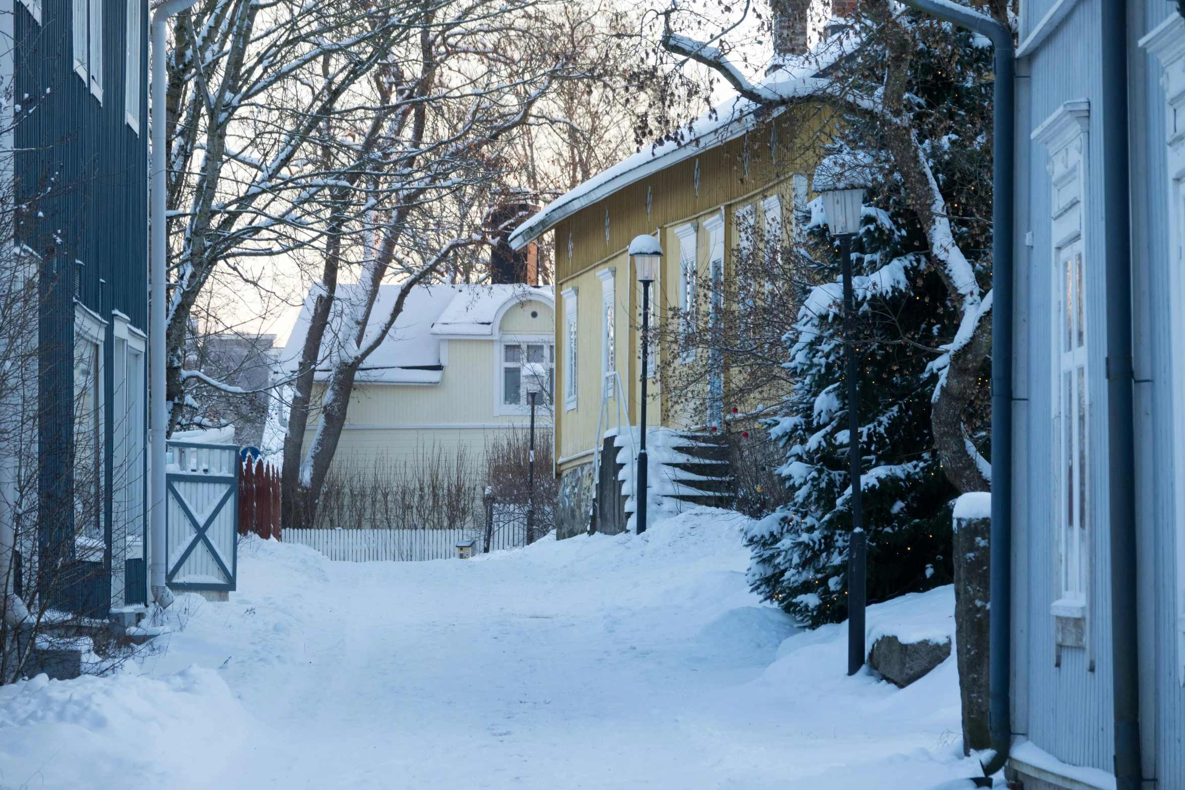 a snowy walkway leads to two yellow houses