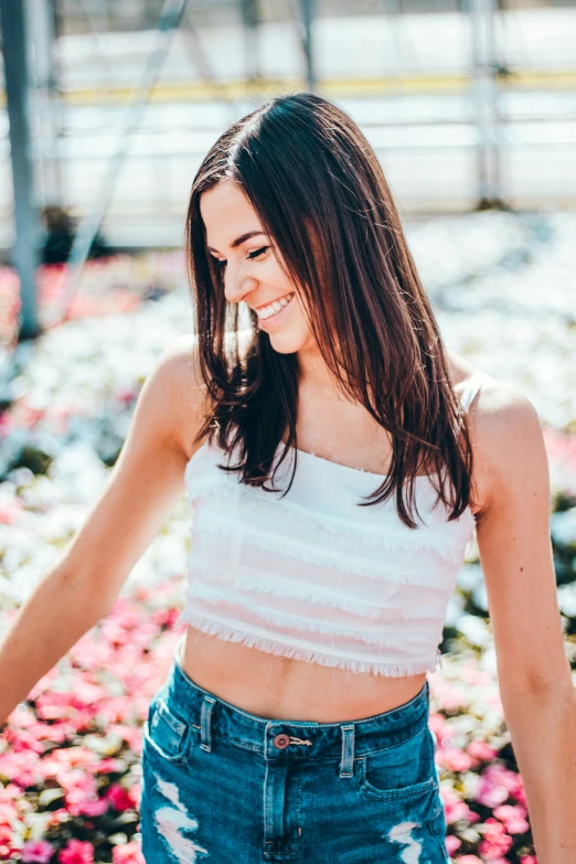 a woman standing on a pink flower garden wearing blue denim shorts