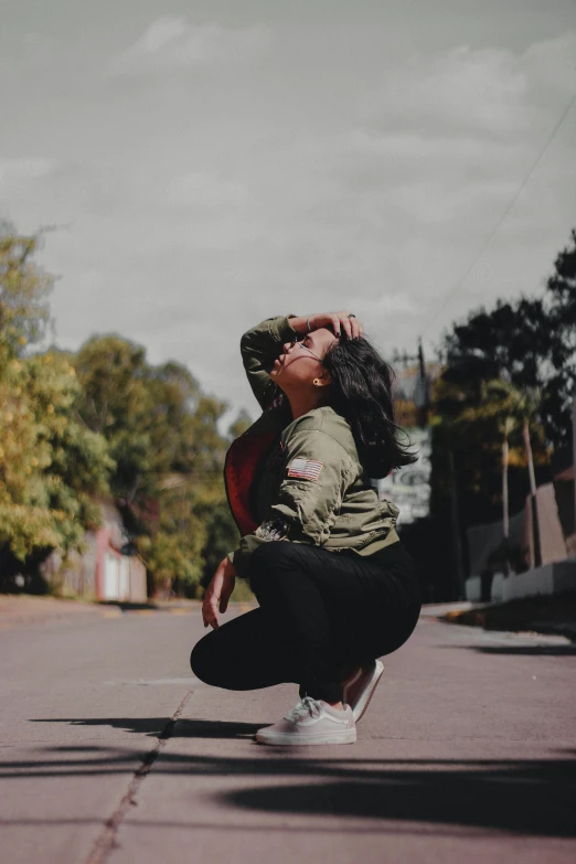 a girl sitting in the middle of the street with her hands to her face