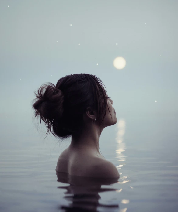 a woman's profile from her back as she sits in the ocean