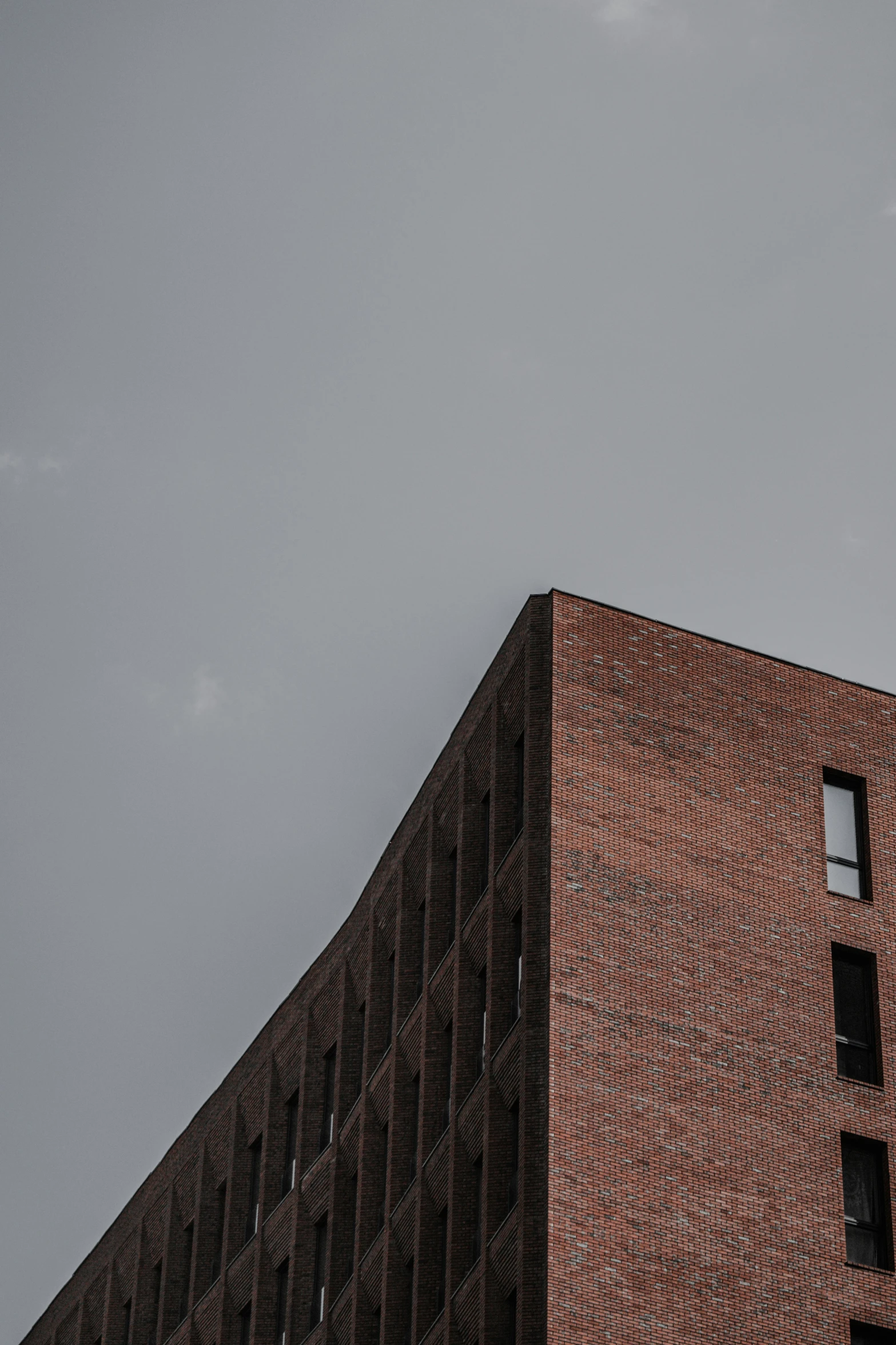 a very tall brick building with windows and some clouds