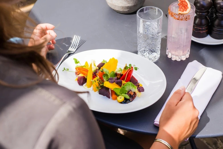 a person's hand is on a plate of food with vegetables