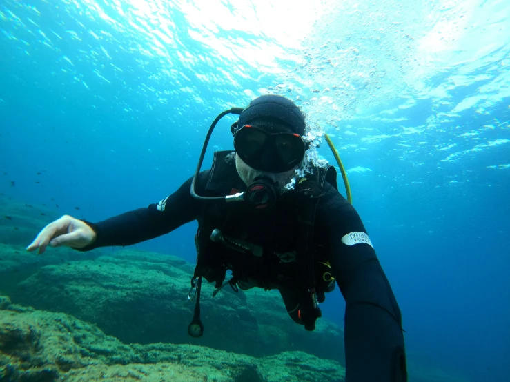 a man on a dive in the water pointing to the bottom