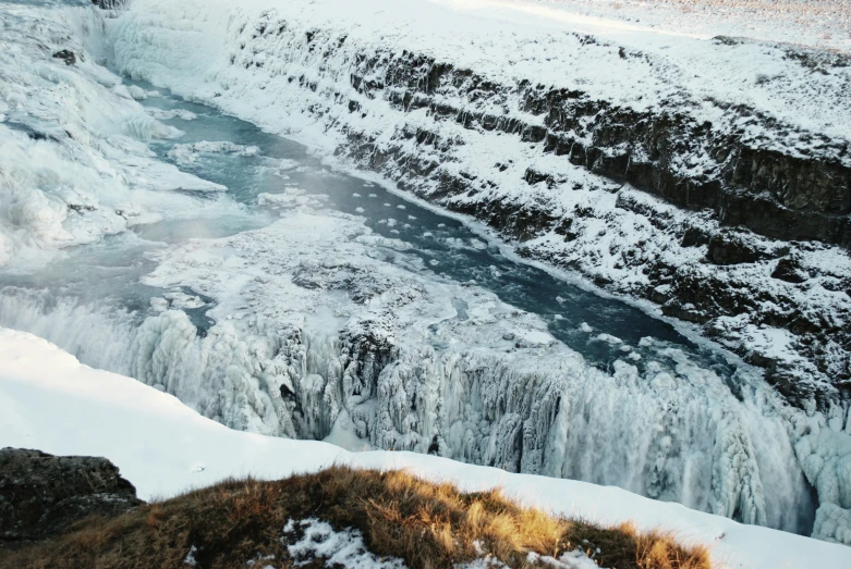 a waterfall with snow on the ground and large rocks