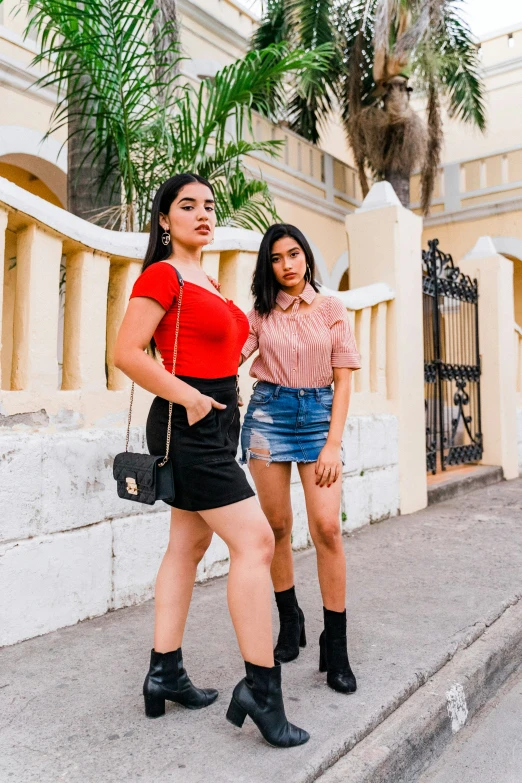 two women stand on a sidewalk with their legs hanging over