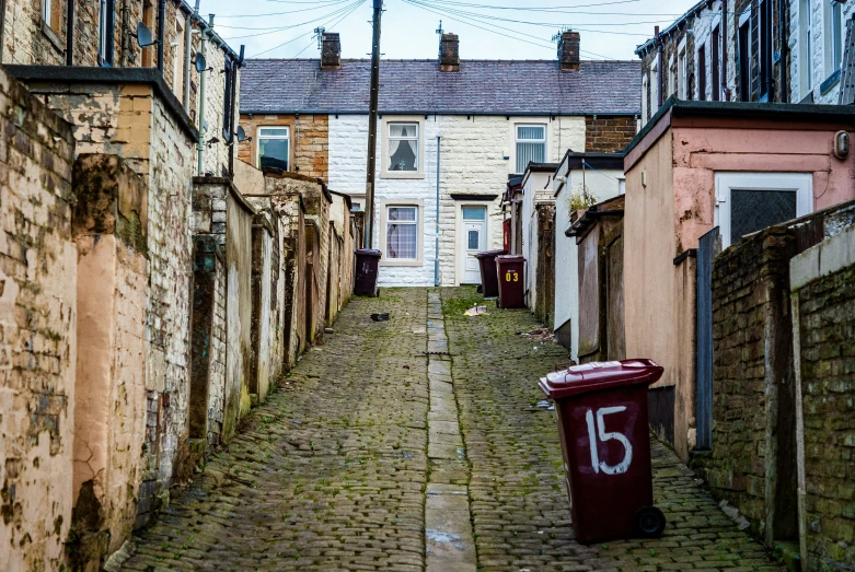 a street view of houses next to a red trash can