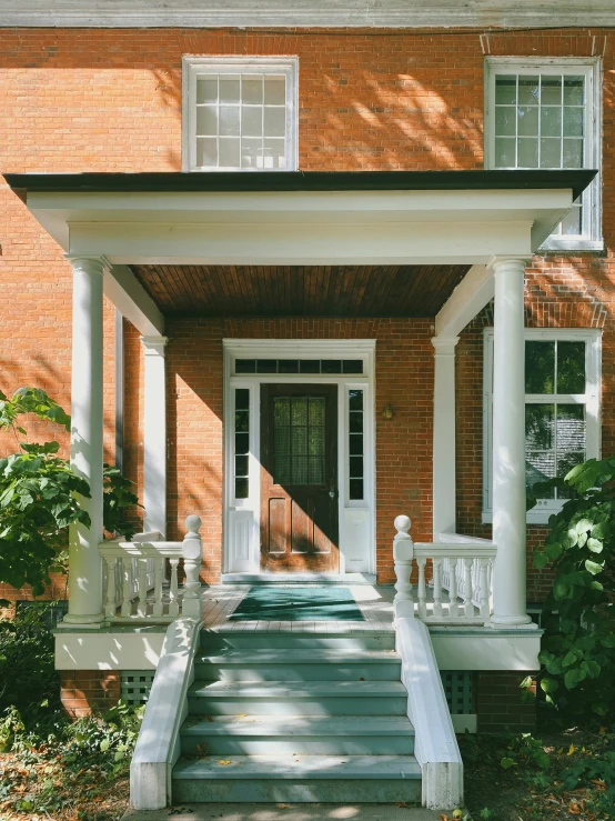 front steps leading to an attached covered entrance with white railings