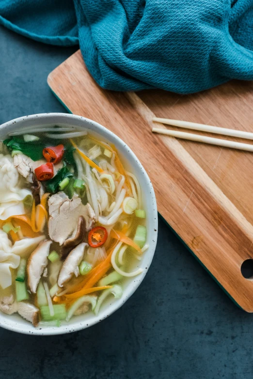 a bowl of soup on a table, with chopsticks