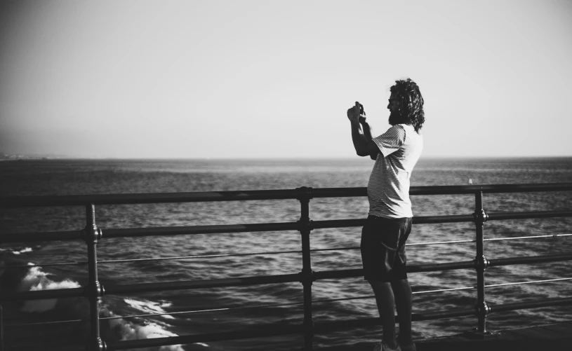 a man in a striped shirt looks out over the water