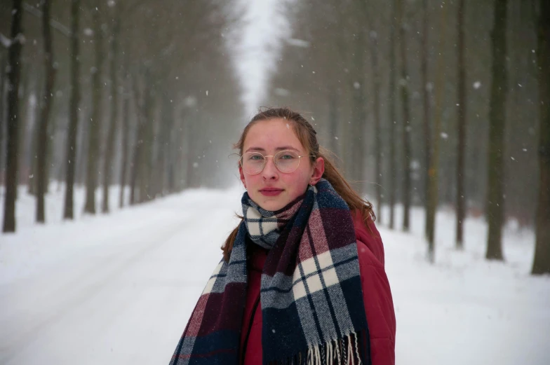 a young lady standing in the snow with her scarf dd around her shoulders