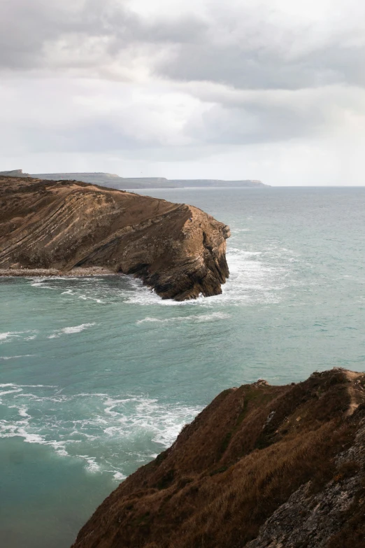 a lone bird standing on the edge of a cliff overlooking water