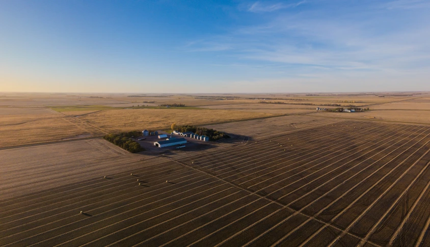 two barns sit on a farm in an open prairie