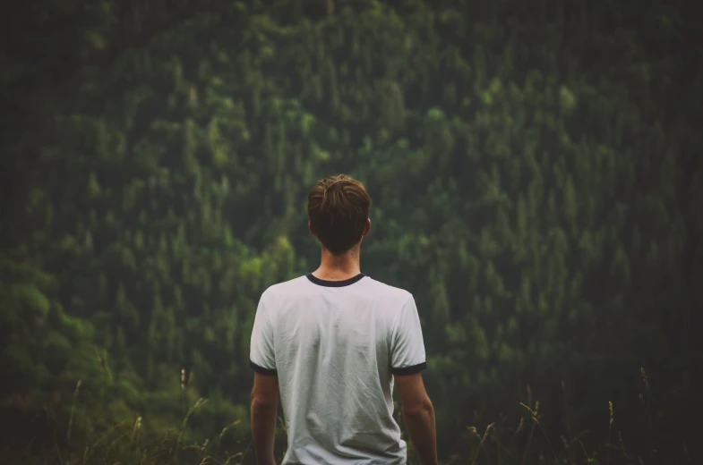 a man standing in the woods looking out into the trees