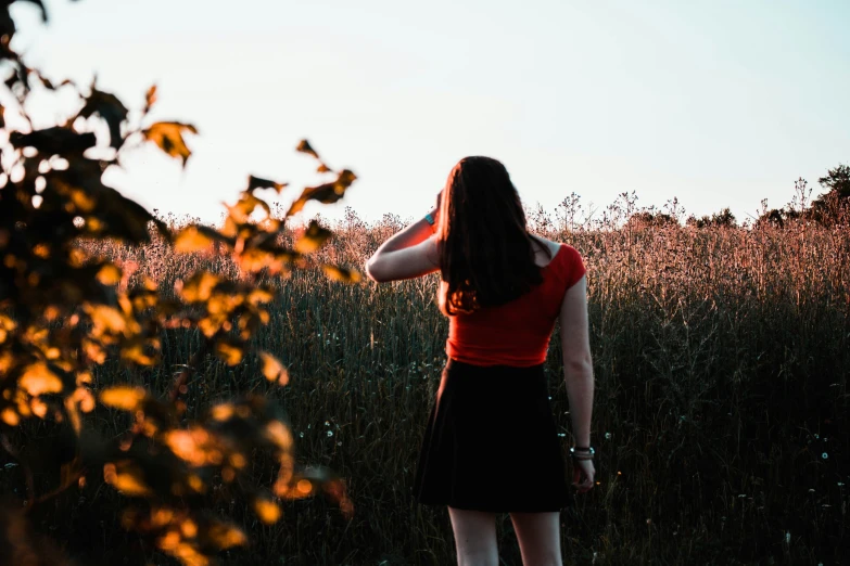 a girl in a red shirt and black skirt is standing on the grass