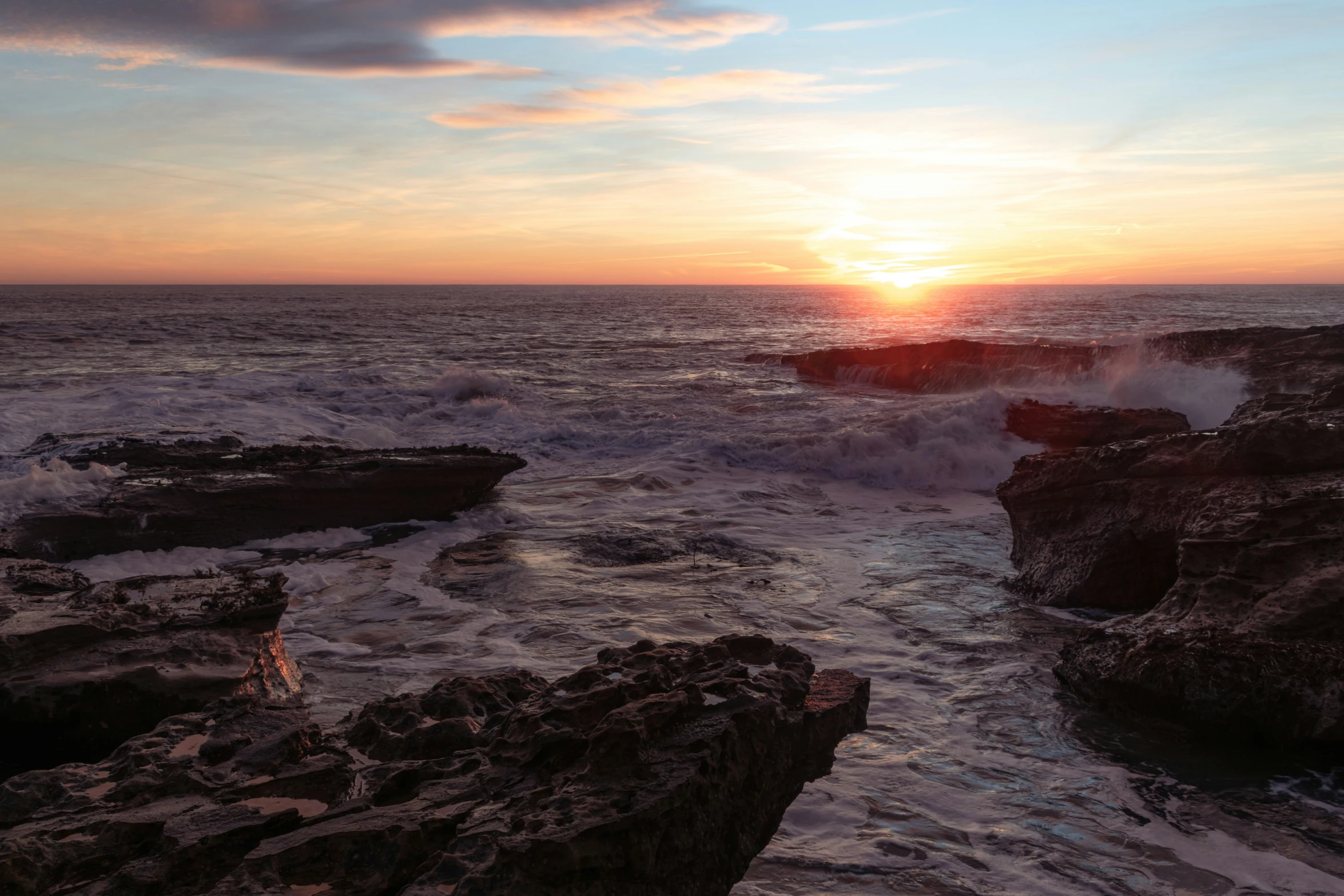 a sunset is reflected off the waves in the ocean