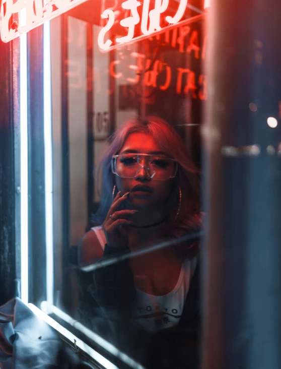a woman in glasses is staring at a neon sign