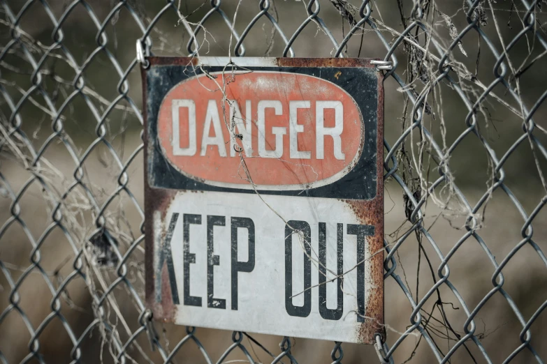 a sign saying danger on it hung on a fence