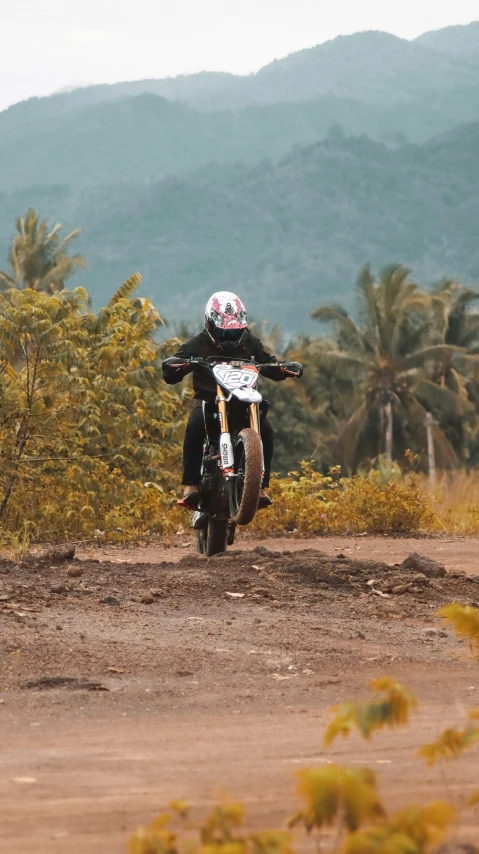 a man on a motorcycle drives down a dirt road