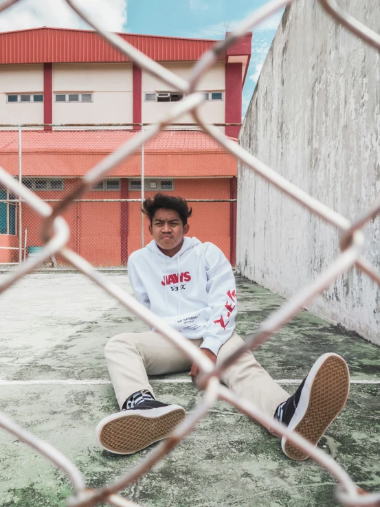 a person sitting on the ground behind a fence