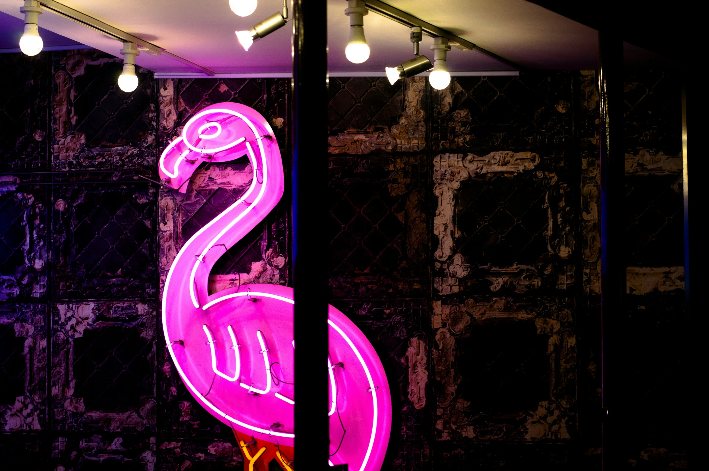 a pink flamingo sits in a building in front of an illuminated sign