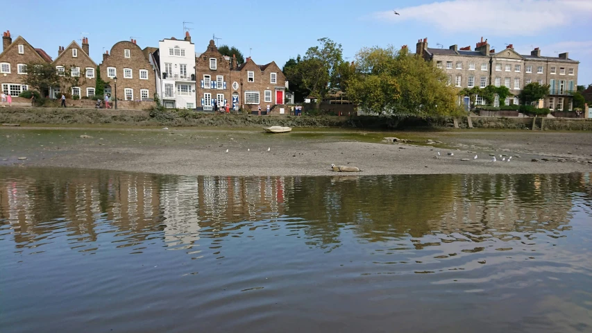 water reflects off the sandy shore near a row of homes