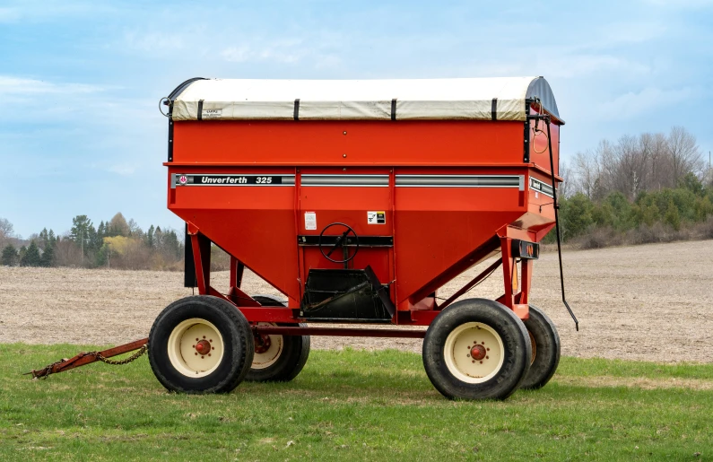 a red machine sitting on top of a lush green field