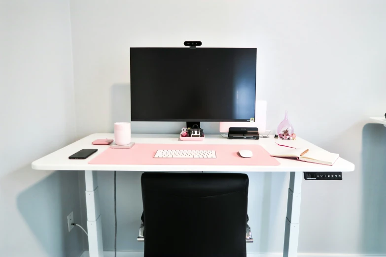 a desk with a computer monitor, keyboard and laptop