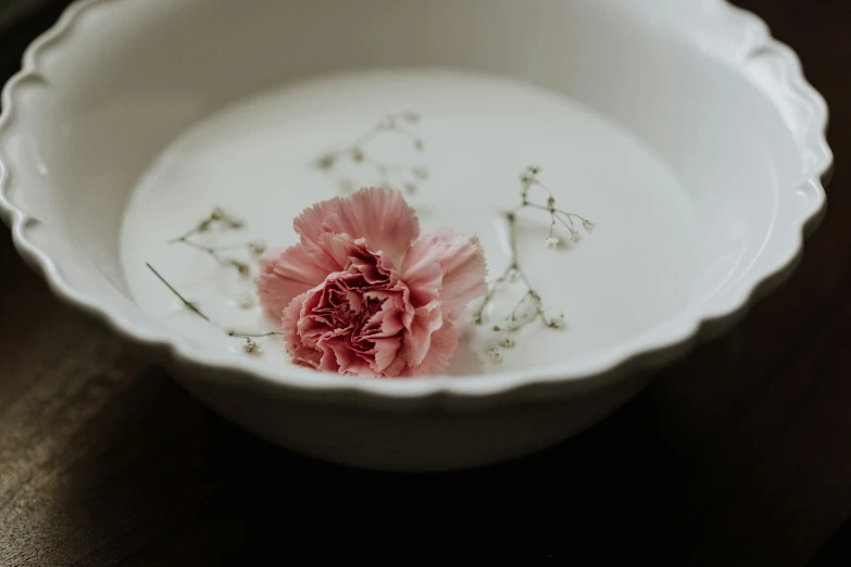 flower in white bowl on a wooden table