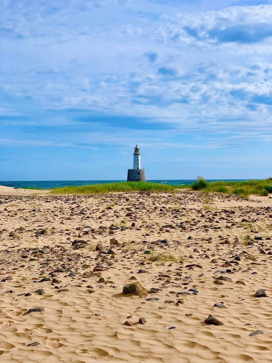 a lighthouse sits on the sand near the ocean