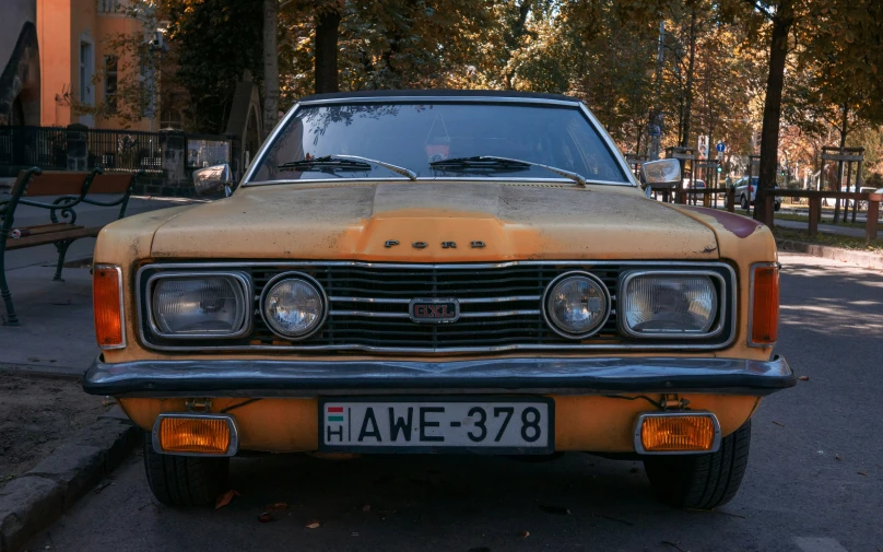 an orange colored old car on the road