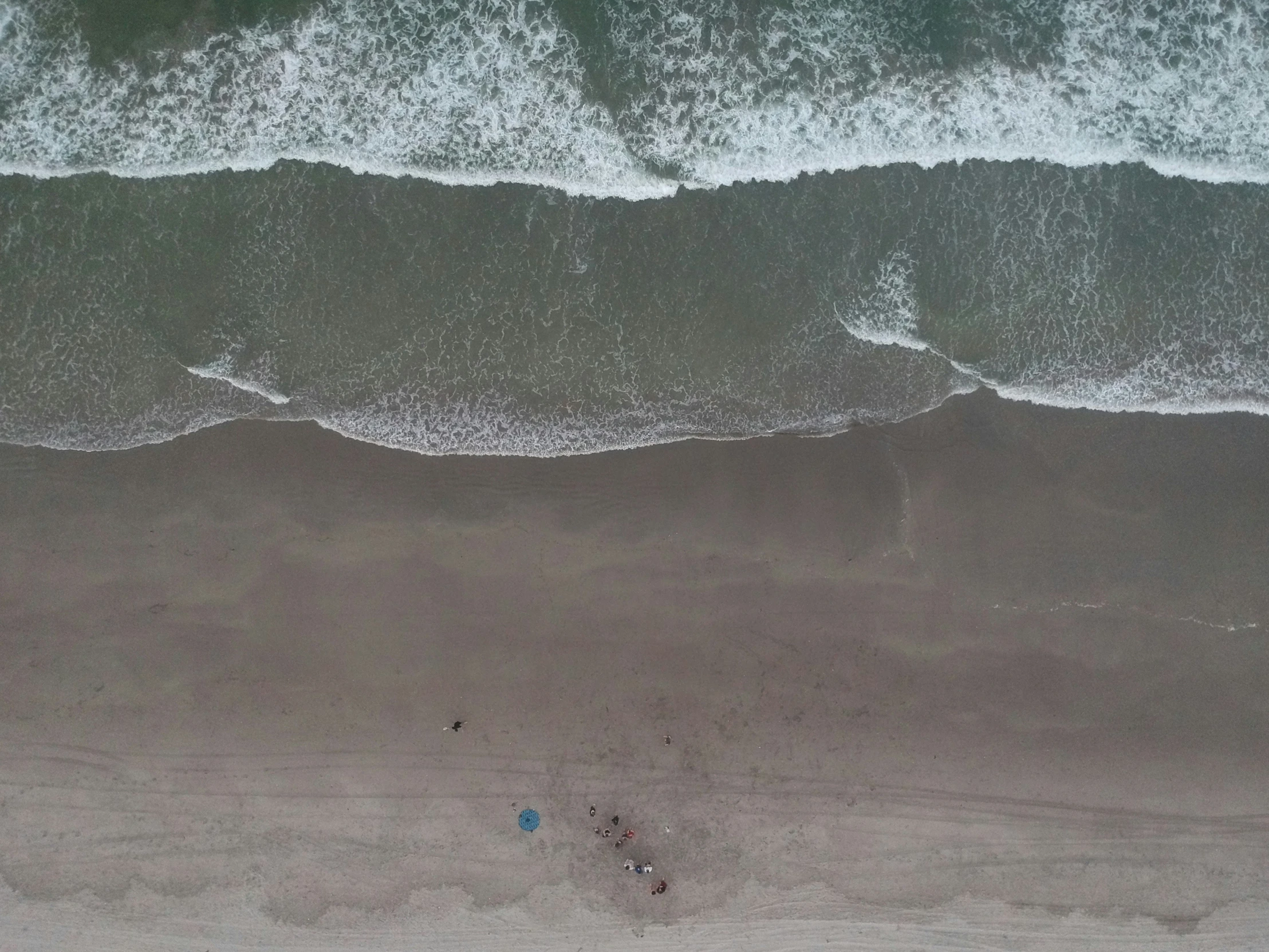 a beach with people walking on it next to the ocean