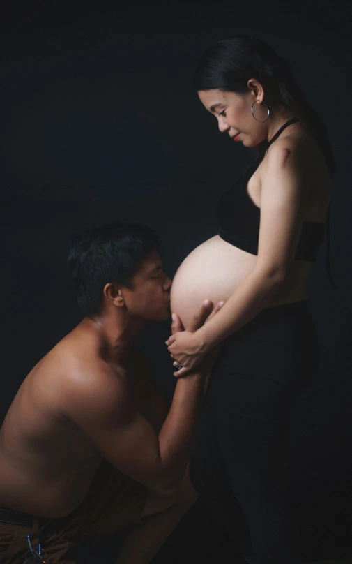 two people, one pregnant and the other , pose for a picture