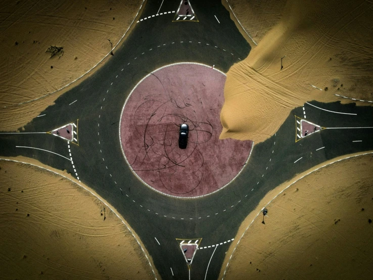 aerial view of asphalted intersection with car coming through the center