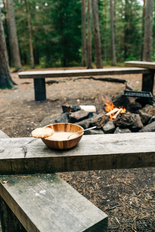 a bowl of food sitting on a cement bench near a fire pit