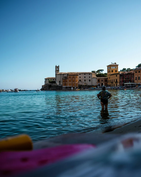 a man in the water is standing in front of a town