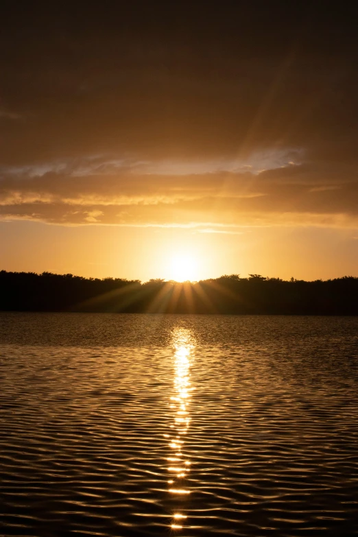 the sun is setting on the lake as the boat sails by