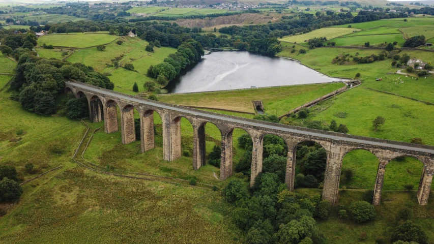 an aerial view of a train with a bridge above it