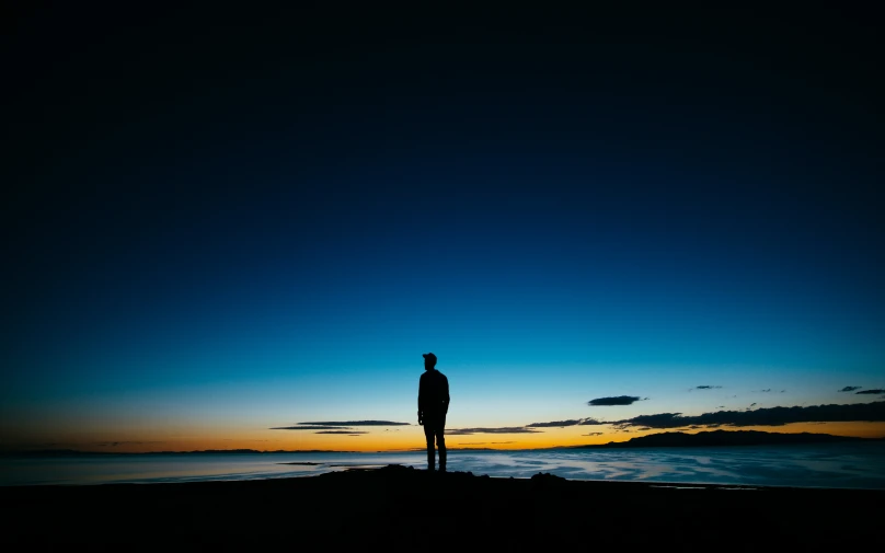 a man standing on a beach during the evening
