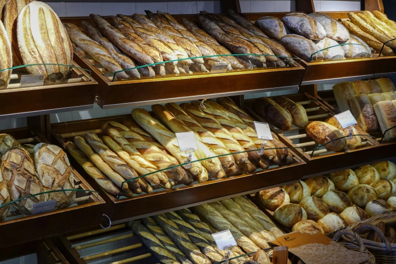 several types of bread and other pastries behind a glass case