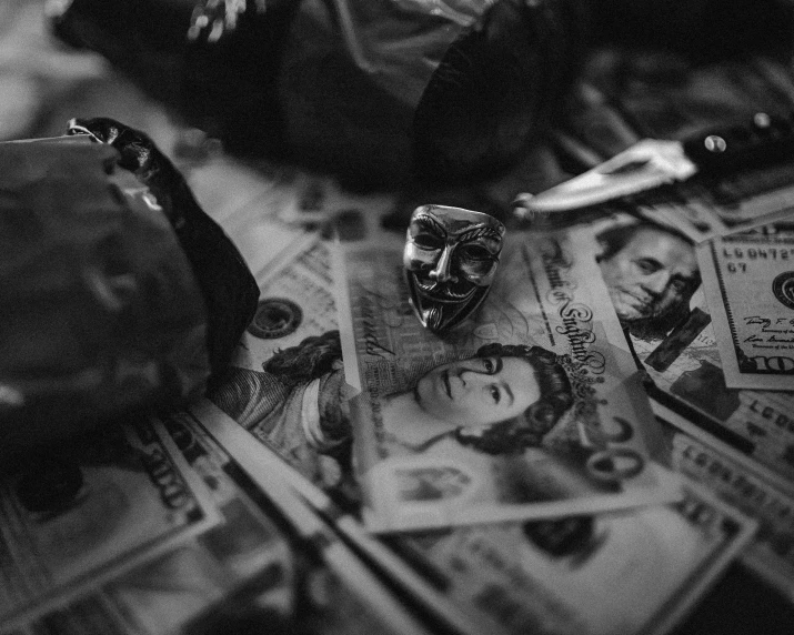 black and white image of a mask sitting on dollar bills